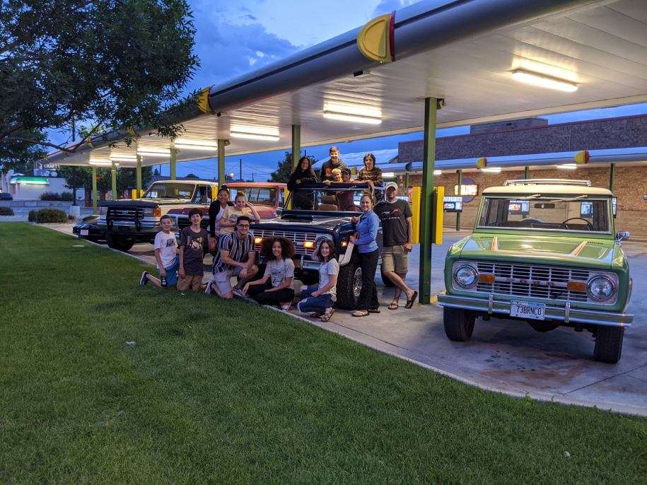 A group of people pose for.a photo around a row of Ford Broncos